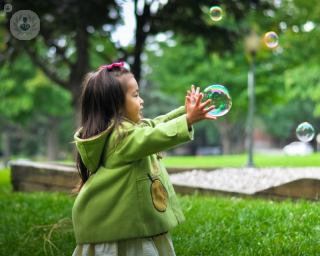 girl wearing green coat playing with bubbles