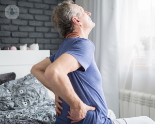 Man holding his back in pain on a bed