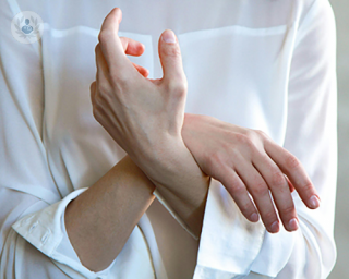 A woman in a white shirt crossing her hands