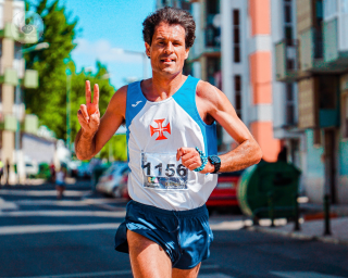 Older man running in a marathon and showing the V peace sign with his hand