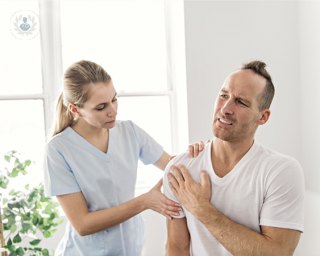 Healthcare worker attending a man with a painful shoulder