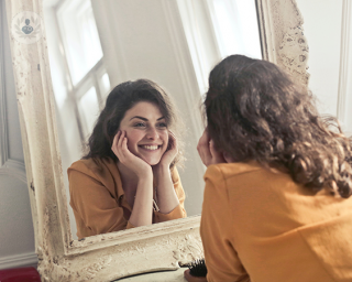 Happy woman looking into a mirror and smiling