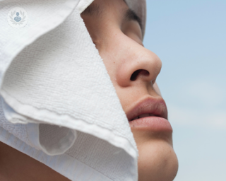 A picture of a women with a towel on her head, showing off her nose