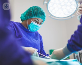 A surgeon in an operating theater performing a surgical procedure.