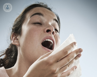 woman sneezing into tissue