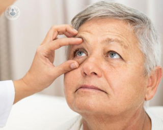 Woman with eye held open by dr examining 