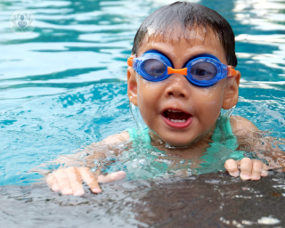Chid wearing blue goggles in a pool