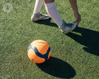 Child stretching their heel next to a football