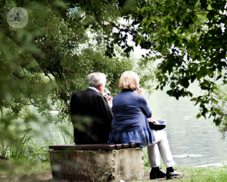Two elderly people sat on a bench looking at a lake