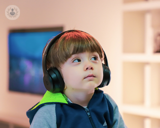 A young boy wearing headphones, looking up to the ceiling.