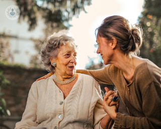 Younger woman with her arm around and talking to an elderly woman