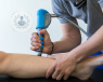 A hand-held shockwave applicator machine being used on a leg