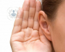 Closeup image of a girl holding up her hand to her ear