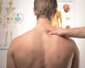 shirtless back of a man, with a doctor hand on shoulder