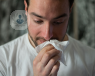 A man holding a tissue towards his nose
