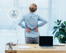 Woman in an office with lumbar spinal stenosis, holding her back in pain