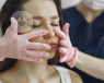 A medical professional's gloved hands lightly pressing on the nose of a patient