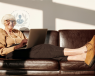 Smiling lady lying on a couch while using a laptop, with calves showing
