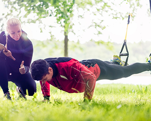 Man doing push ups with a trainer, as part of a fitness plan