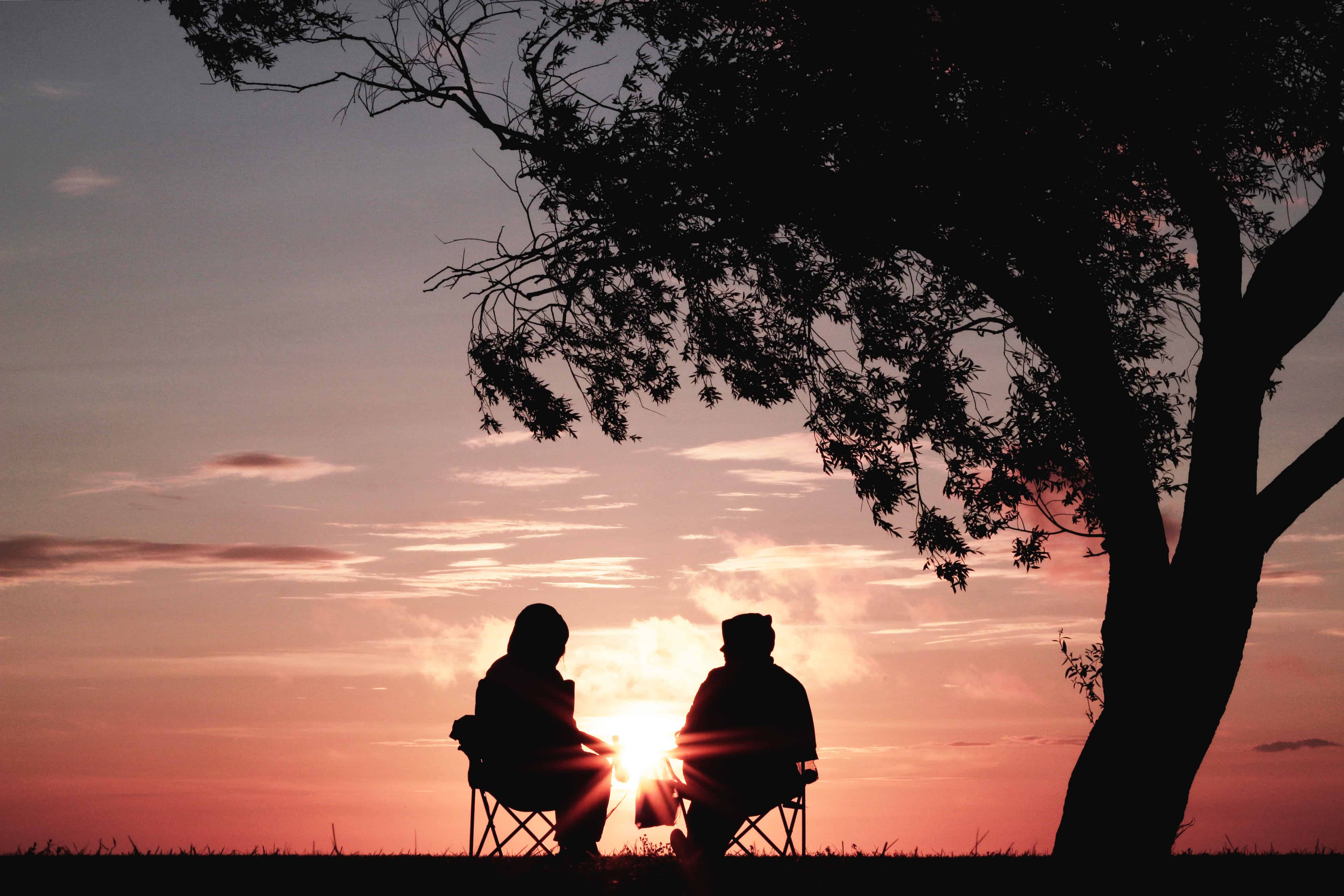 Two people sitting together at sunset. A problem shared is a problem halved, and talking to a friend or family member can help you deal with your emotional eating triggers.