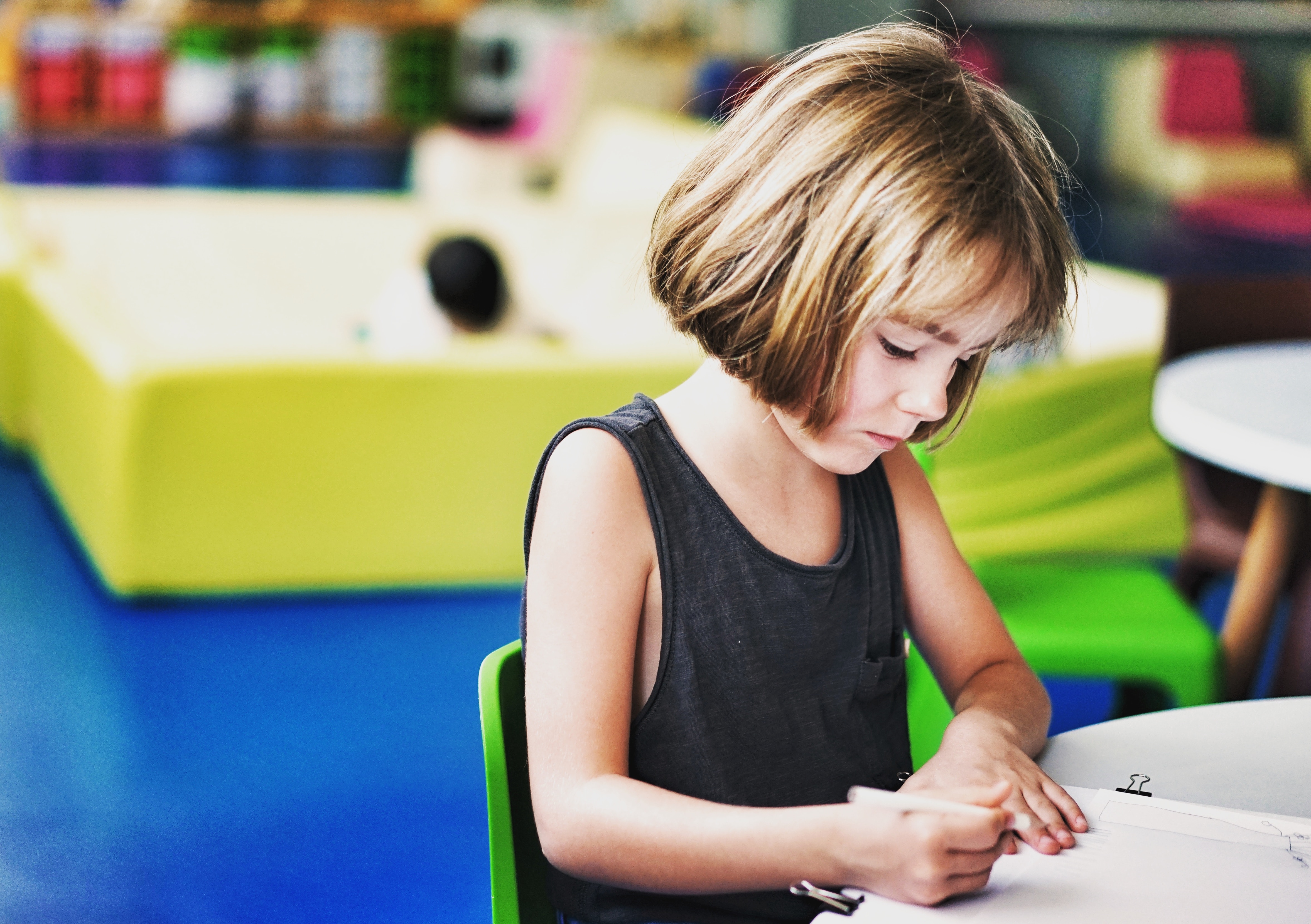 Child sitting at a table by herself and writing.