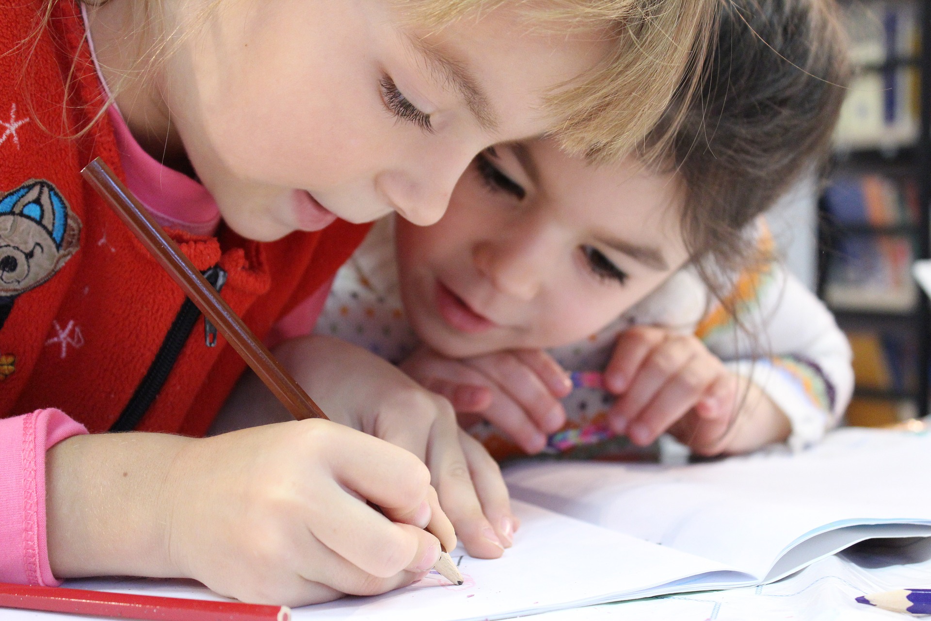 Two young girls working on a schoolbook exercise