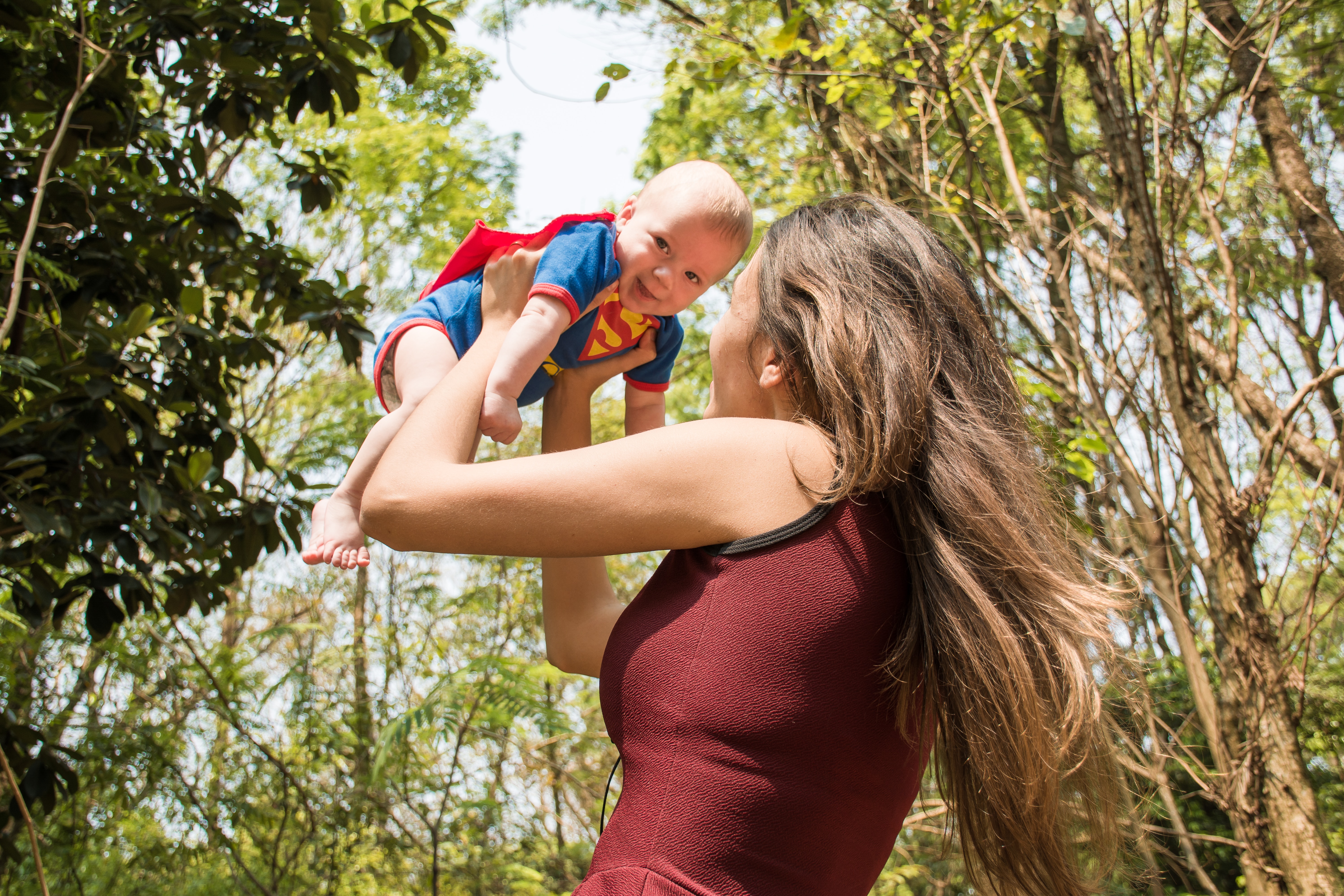 Mother holding baby in Superman onesie.