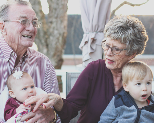 World Health Day 2023: Happy grandparents and grandchildren sat outside.