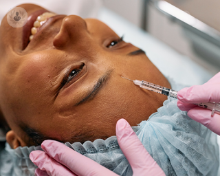 A clinician administering a facial aesthetics injection into a patient's forehead.