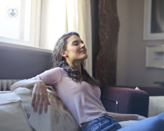 Woman sat on the sofa looking relaxed and relieved