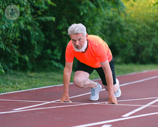 An elderly man on a running track prepared to go on a sprint