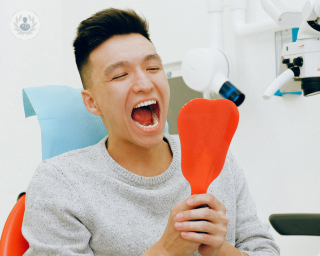 Man at the dentist looking in his mouth through a hand mirror