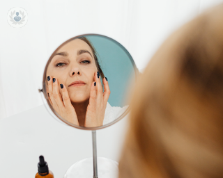 A woman looking at her face in the mirror