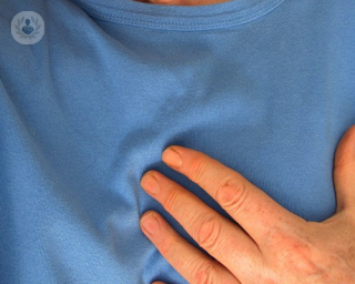 an image of a man in a blue jumper holding his heart