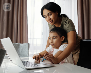 Mother and little girl working at laptop