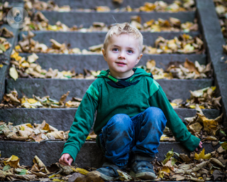 A young boy of around five years old is sitting on stone steps.