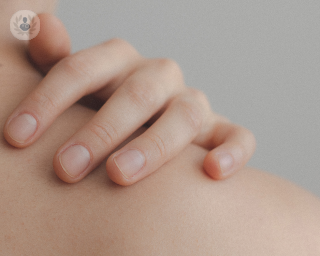 Close up of woman's hand touching her shoulder