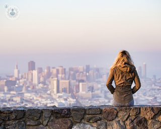 woman sitting on a wall overlooking a city