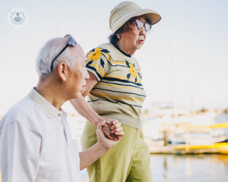 Older couple, at risk of having osteoporosis, walking by a sea wall