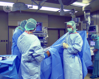 Patient undergoing knee surgery surrounded by three surgeons