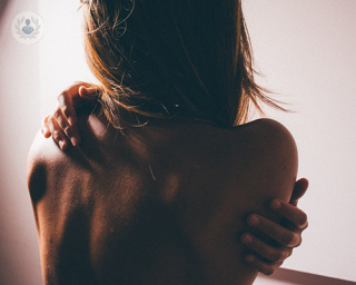 Woman's back without clothes, her hugging herself