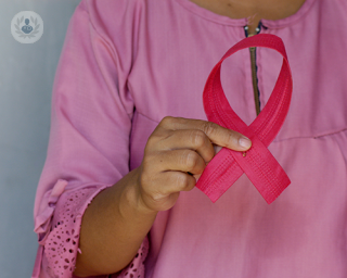 A woman holding the breast cancer pink ribbon.