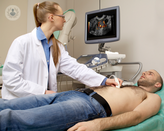 A doctor is using an echocardiogram on a patient. The machine's monitor shows images of the heart that are generated through ultrasound.