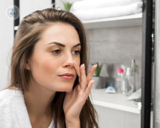 Woman looking at herself in the mirror and touching her nose