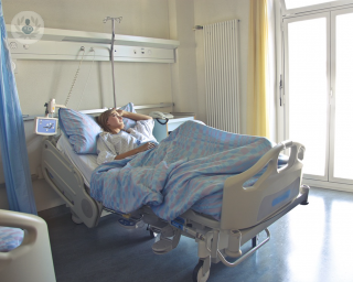 Woman lying in a hospital bed alone looking out the window