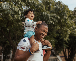 Man carrying a child on his shoulders outside