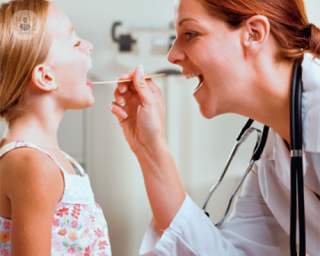Doctor examines mouth of child who needs adenoid surgery