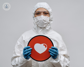 Doctor wearing hazmat suit and mask, holding a heart sign