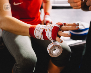 an outstretched arm of an athlete or sportsperson with a protective cast and tape around their hand. A trainer is on the right and ready to apply more tape.