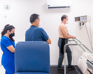 A patient walking on a treadmill machine in a consulting room, during a stress echocardiogram test.